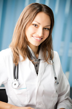 Portrai of happy smiling young female doctor at office