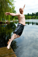 Fototapeta na wymiar man jumping off dock into a lake.