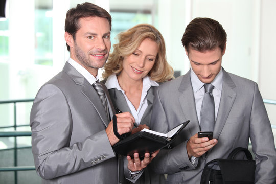 Businessmen and woman checking diary