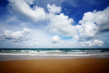 The sea with waves and blue sky with fluffy clouds