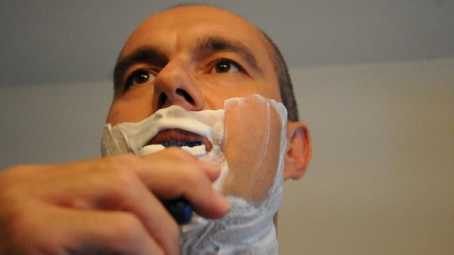 Mann rasiert sich im Badezimmer