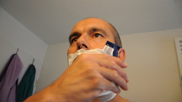 Mann rasiert sich im Badezimmer