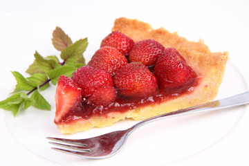 Piece of Strawberry Tart on white plate with mint twig