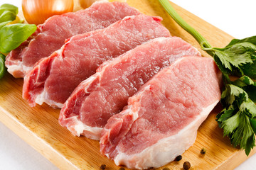 Raw pork on cutting board and vegetables