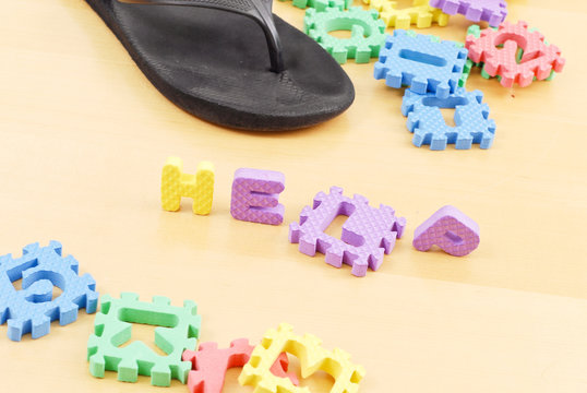 Letters Spelling the Word Help on Floor with Mommys Slipper
