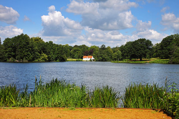 An English lake with whitewashed house in the distance © Chris Lofty