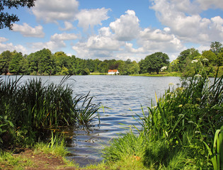 An English lake with whitewashed house in the distance © Chris Lofty