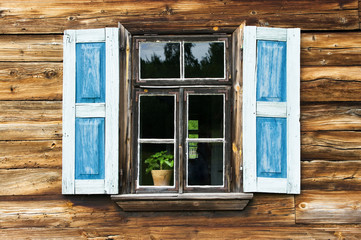 Window with blue shutters in old wooden wall