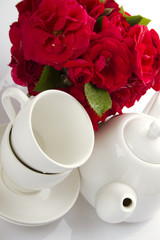 White crockery for tea and a bouquet of roses
