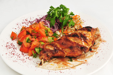 Meat on a bone prepared on a grill with vegetable salad