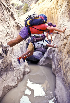 Hikers navigate a slot canyon.