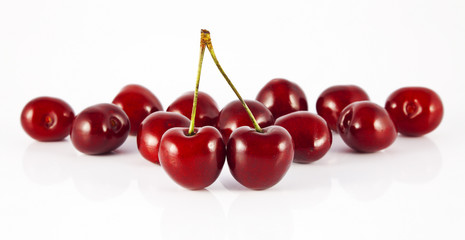two cherries with stems in front of cherry
