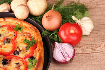 tasty pizza with olives and vegetables on a wooden background