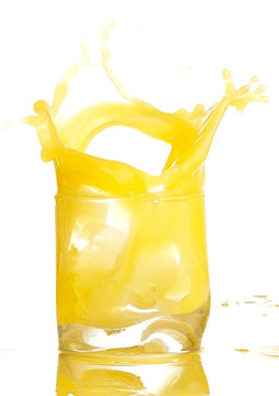 orange juice splashing on a glass on white background