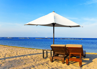 Umbrella and chaise lounges on a beach.