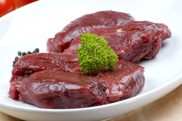 raw ostrich steak with parsley on a plate