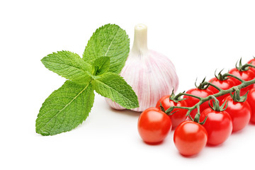 A studio shot of mint leaves, garlic and cherry tomatoes