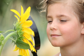 Child examining a sunflower with a magnifying glass