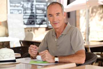 Older man drinking an expresso outside a cafe