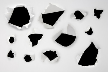 Closeup of a dark holes on white paper set - obrazy, fototapety, plakaty
