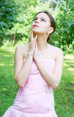 Young woman in pink dress near trees