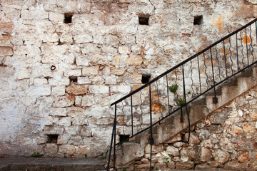 Stairs with railing against the old stone walls