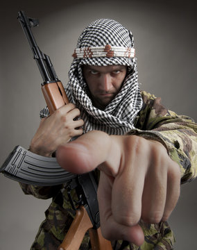 Man with gun pointing while standing against gray background