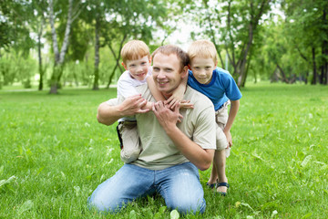 Naklejka na ściany i meble Portrait of father with two sons outdoor