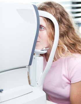 optometry concept - pretty young woman having her eyes examined