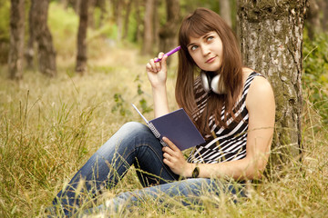 Young teen girl doing homework at the park.