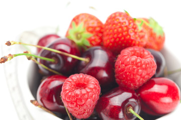 raspberries, strawberries and cherries in a bowl isolated on whi