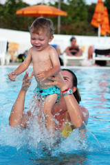 Fototapeta na wymiar Cute baby playing in the swimmingpool with his mother