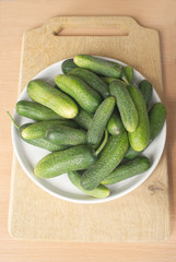 Many green raw cucumbers on brown cutting board