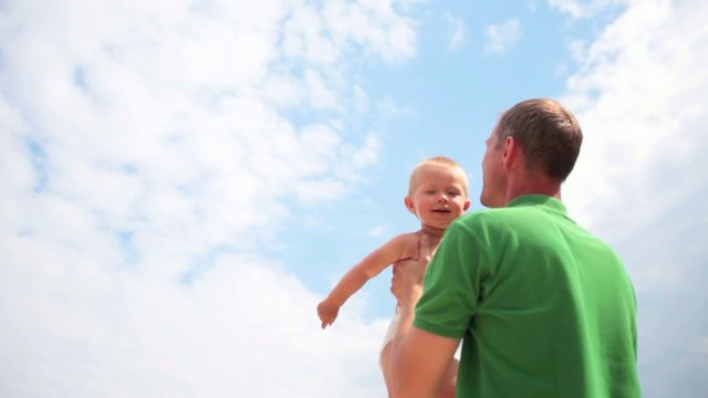 Father tossing baby on sky background