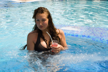 Girl with a cocktail in the pool