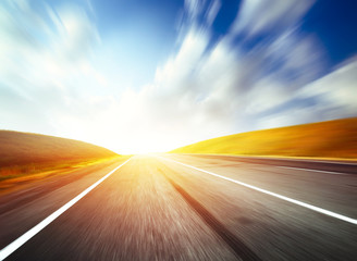 Naklejka premium Empty motion blurred asphalt road and blue sky with blurred clouds