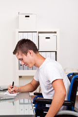 mann sitzt im rollstuhl am arbeitsplatz