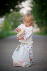 Adorable toddler girl draggin bag with food from supermarket by