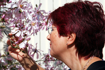 Fototapeta premium Frau riecht an einer Magnolienblüte