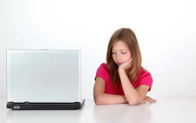 Girl with thoughtful look next to laptop computer