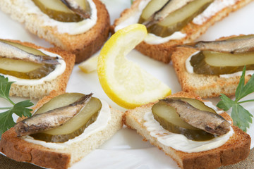 Sandwiches with sprats on a white plate - obrazy, fototapety, plakaty