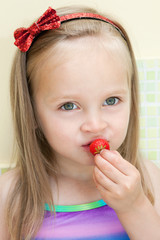 Little girl eating strawberry