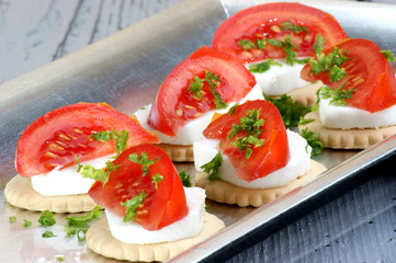 Cracker mit Mozzarella, Tomatenviertel und gehackter Petersilie