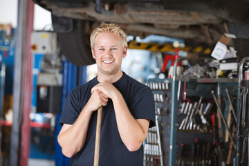 Smiling mechanic holding broom