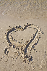 Sign of the heart in the sand. Tidal wave