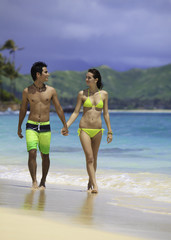 Fototapeta premium couple at the beach walking along the water's edge