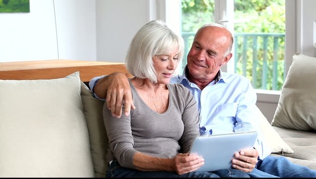 Senior couple using electronic tablet at home