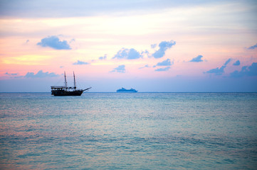 Obraz premium Boat in a landscape of sunset colors over the ocean.
