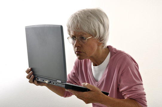 Seniorin hat Schwierigkeiten den Laptop zu lesen