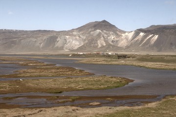 Mehrfarbiger sandiger Hang mit Wasserlandschaft im Vordergrund